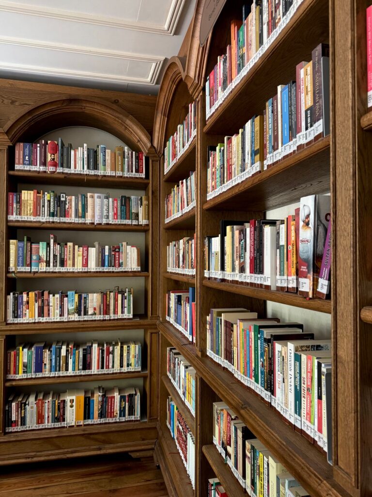 Carnet deschis cu un citat scris de mână, pe o masă lângă rafturi de bibliotecă